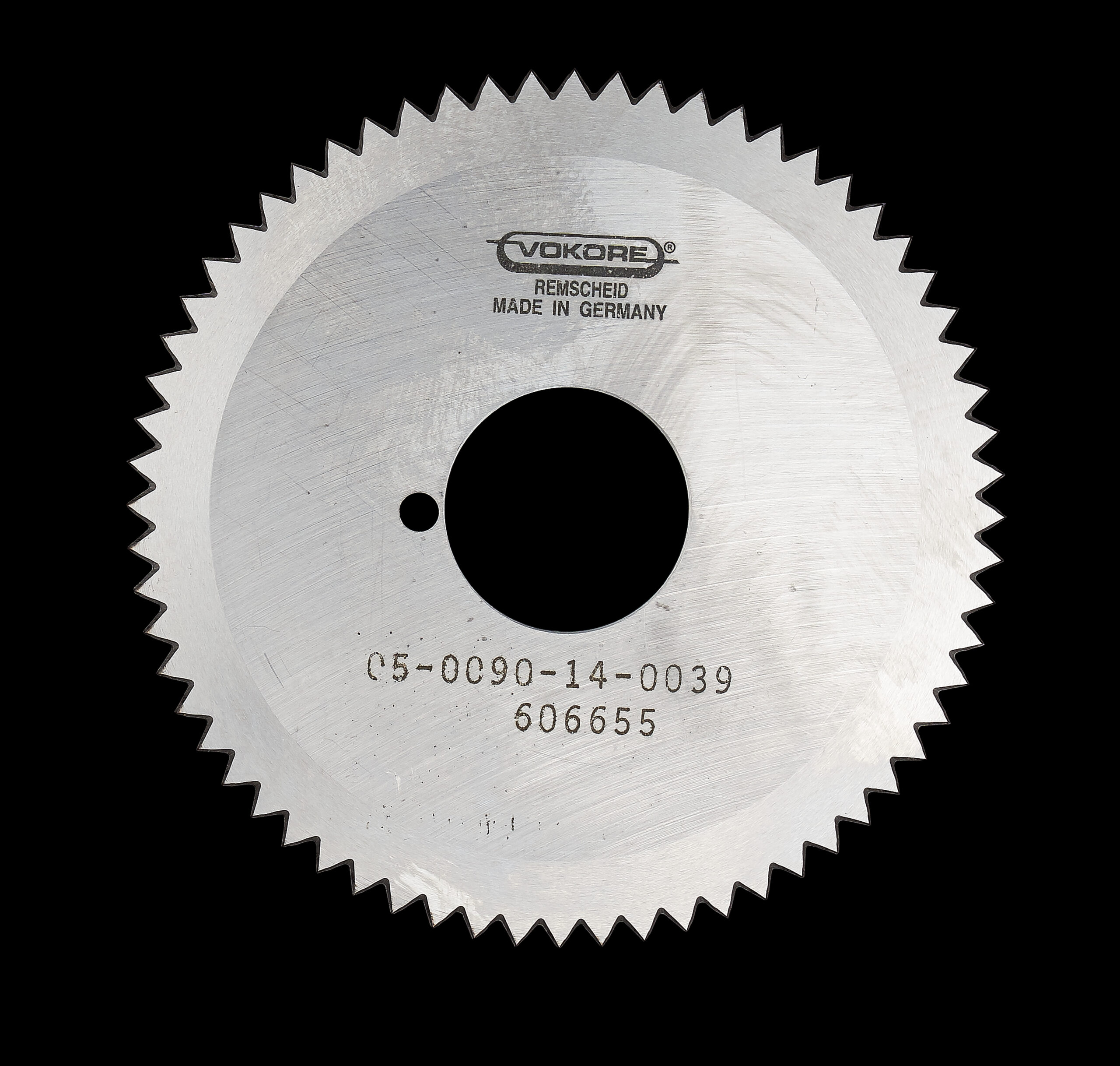 Kreisschere_3 Rundes Kreissägeblatt mit feiner Zahnung und zentraler Bohrung, Gravur Vokore sichtbar, dargestellt vor schwarzem Hintergrund